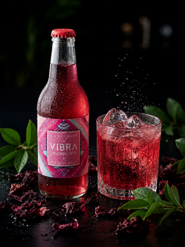 Vibra Flor de Jamaica servida con hielo, ginger beer natural color rosado